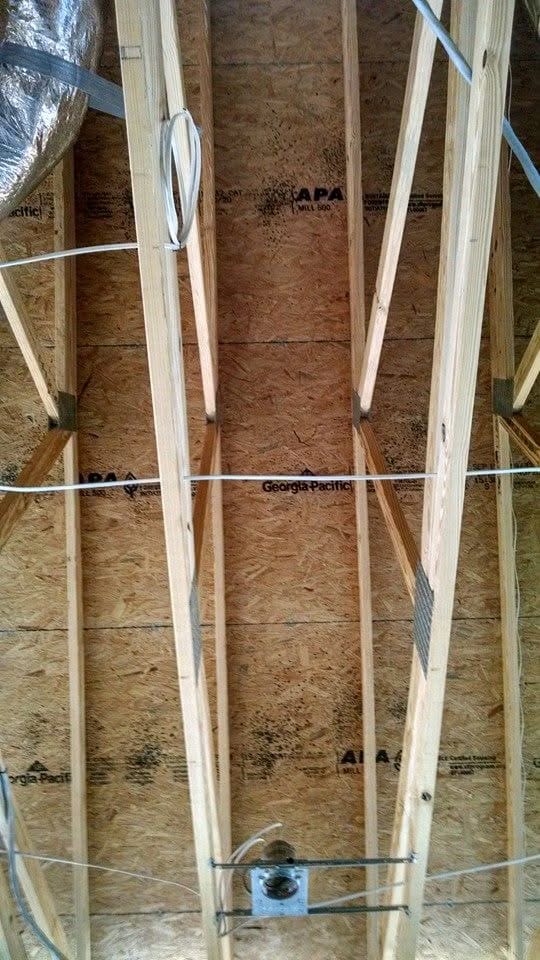 Bare, un-insulated OSB roof deck and trusses in an empty Panhandle home, running hot on a summer afternoon