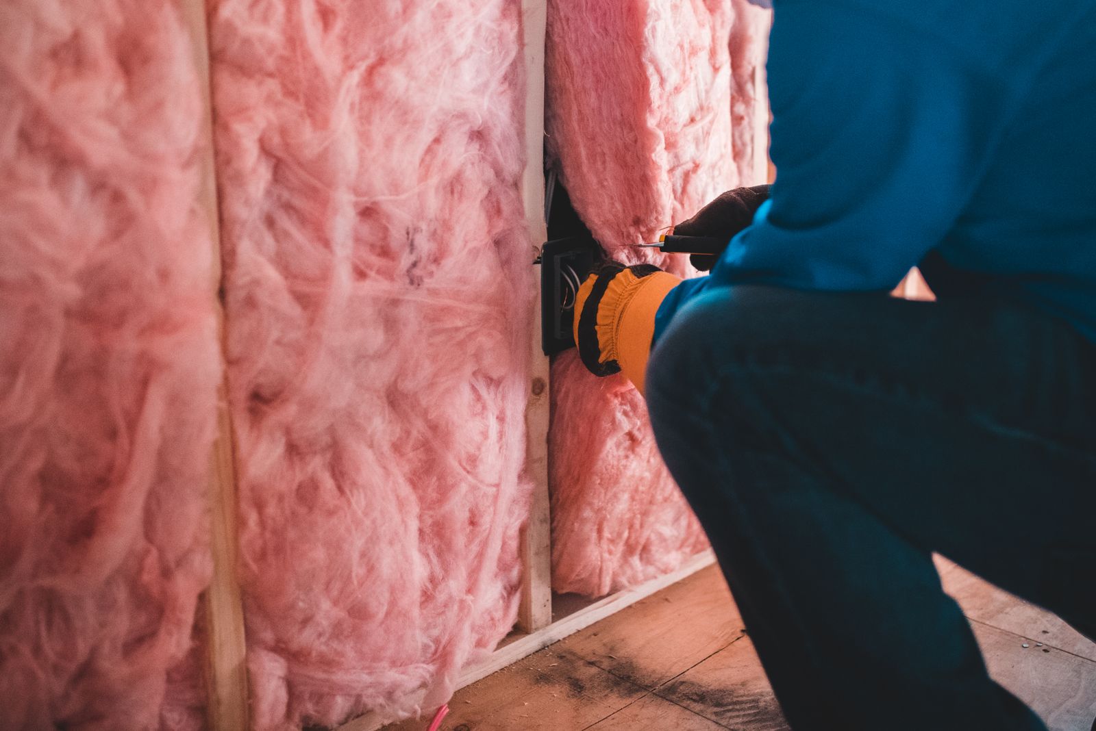 Fiberglass batt insulation being fitted into a stud wall cavity